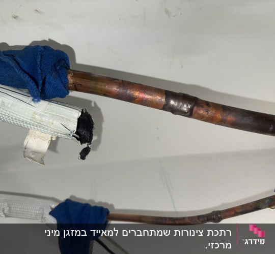 צינורות נחושת עם בידוד כחול על רקע קיר לבן
